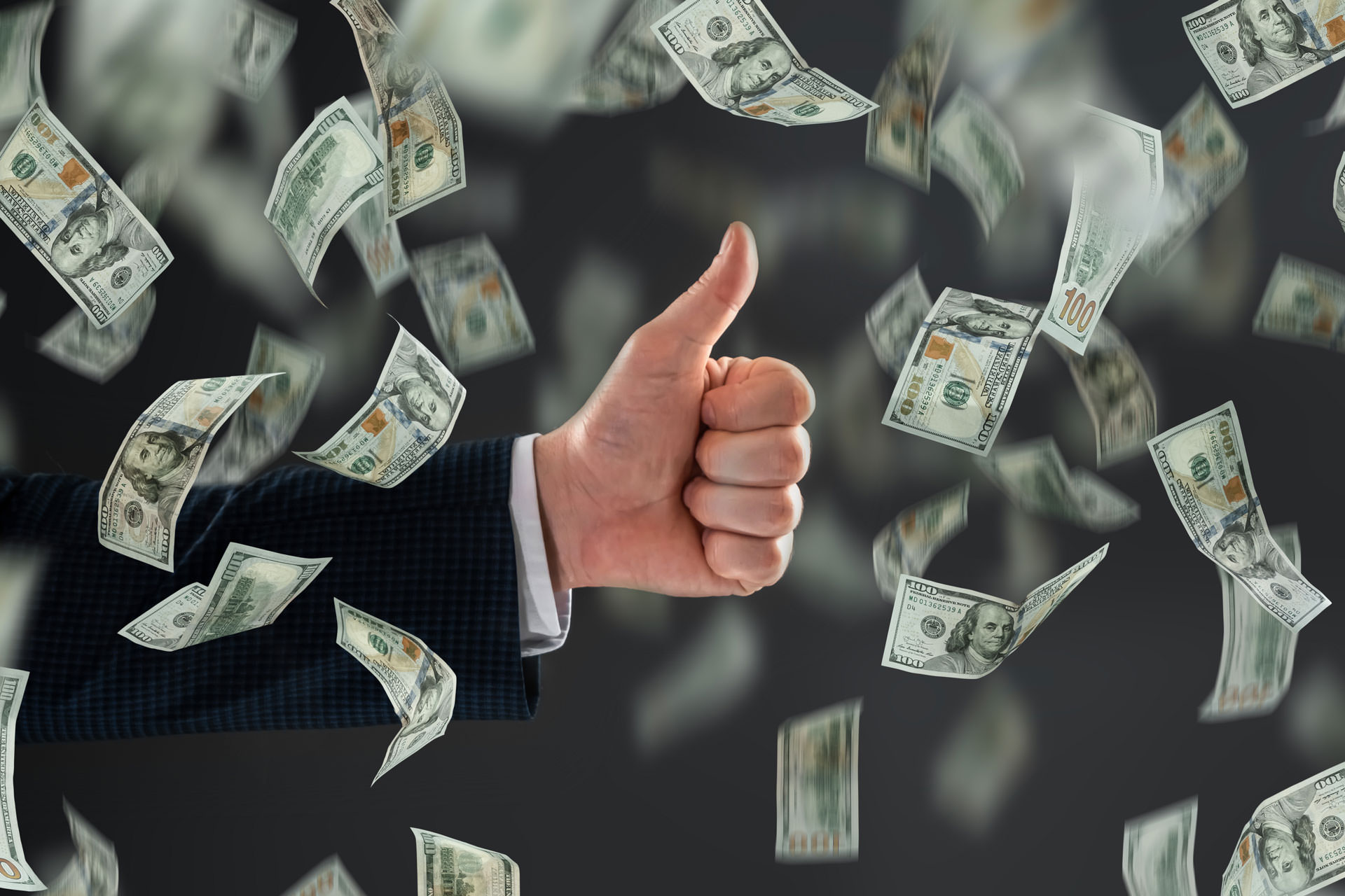 A professional hand giving a thumbs up with money falling around the hand.